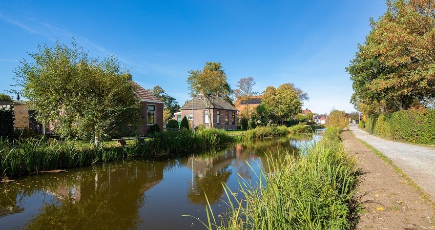Foto van huizen aan een vaart met ernaast een weg